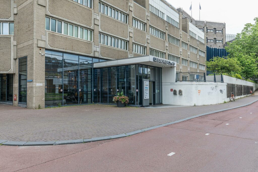 Ingang van het kantoorgebouw Leidseveer 2-10 in Utrecht met grote glazen gevel en straatzicht.
