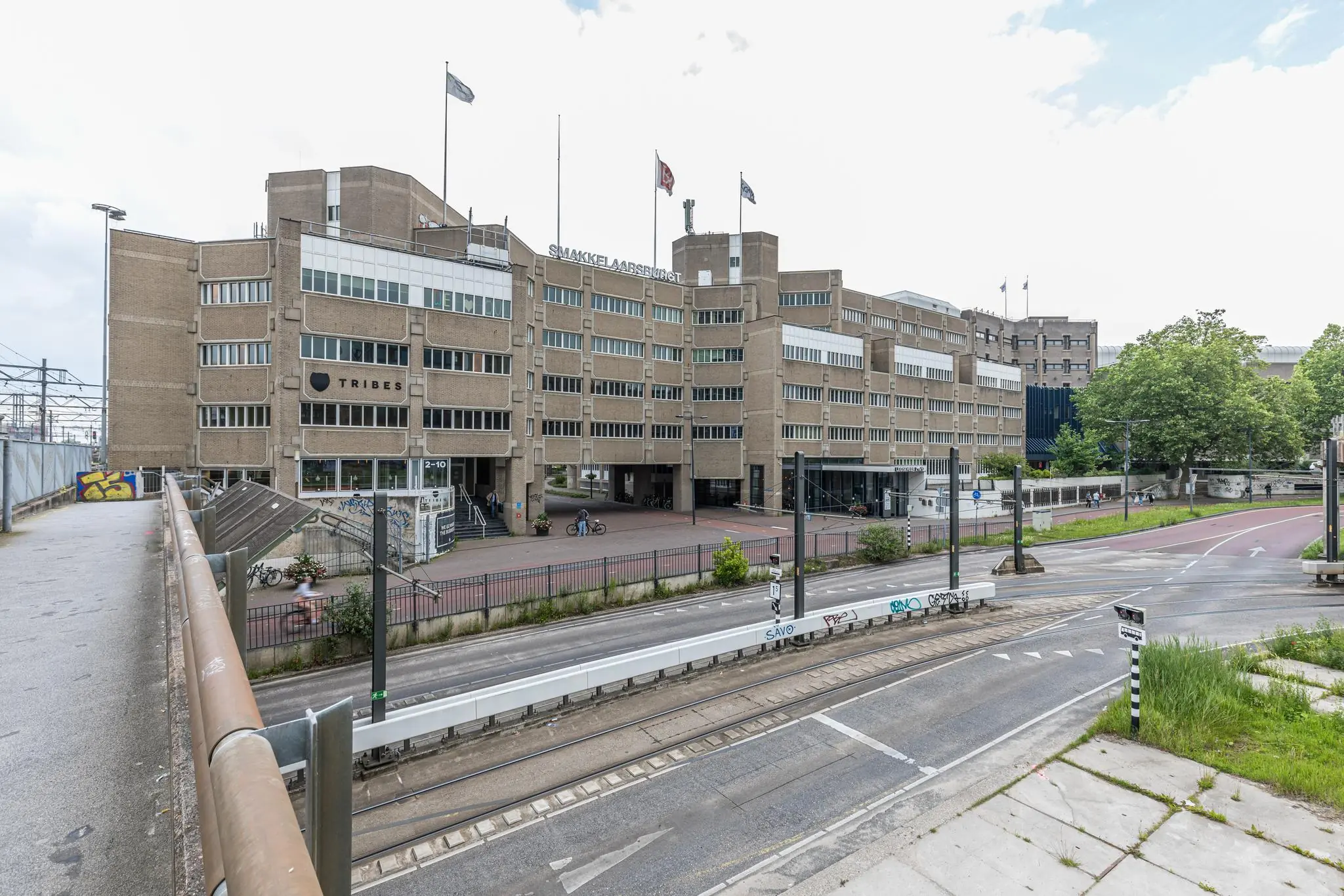 Vooraanzicht van het gebouw "Smakkelaarsbrug" aan het Leidseveer in Utrecht, met tramrails en fietspad op de voorgrond.