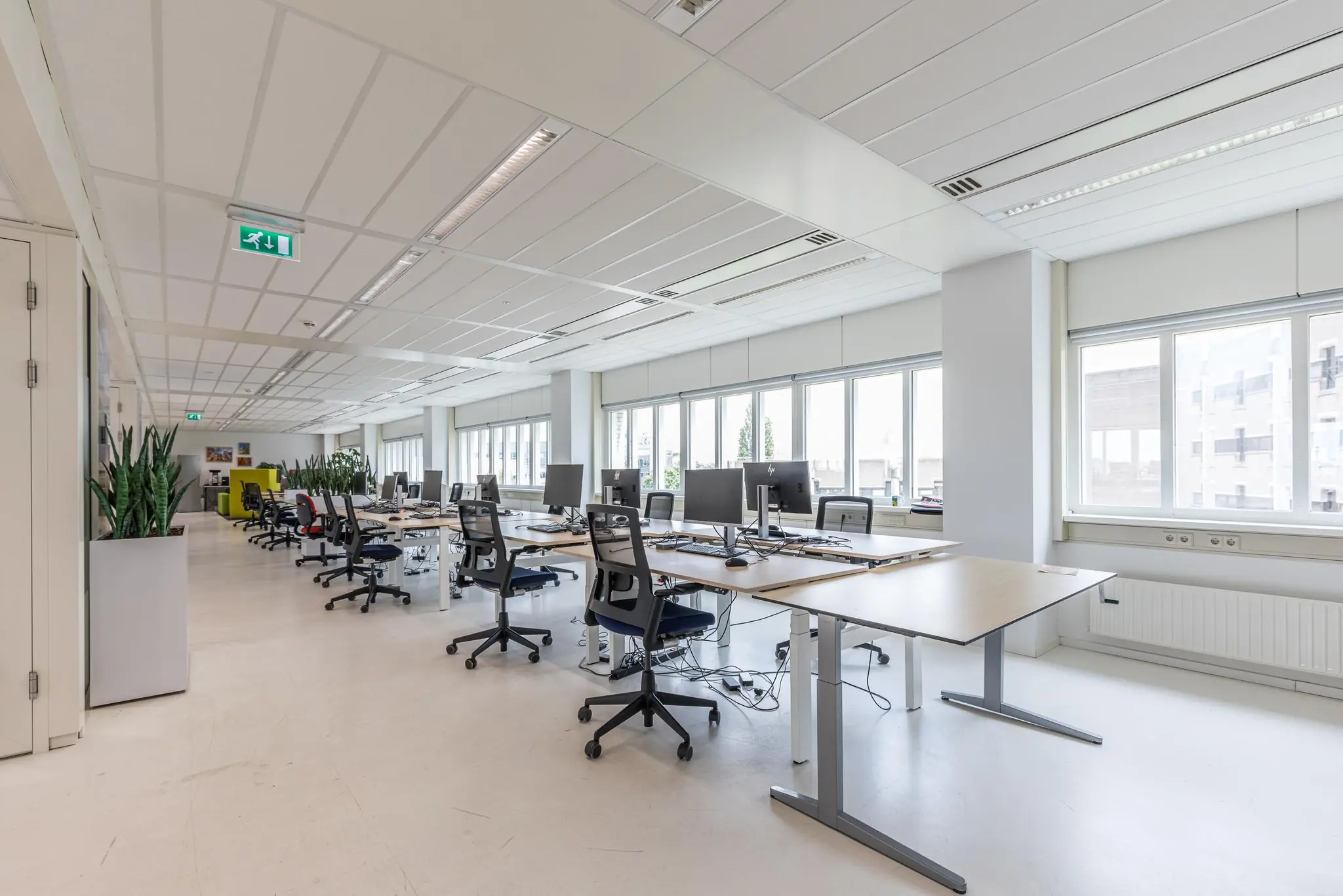 Modern en licht kantoorinterieur aan het Leidseveer met werkplekken, bureaustoelen en computers.