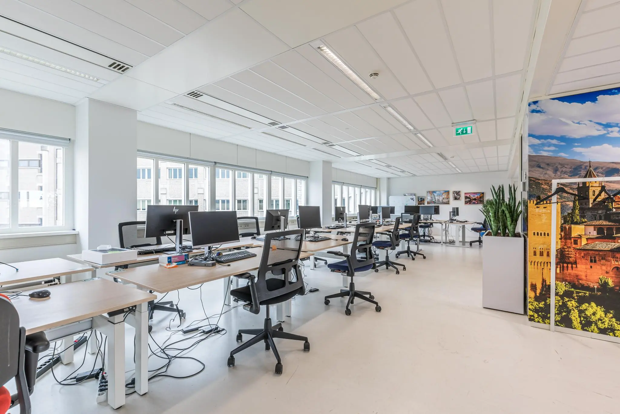 Moderne, lichte kantooruimte aan het Leidseveer met meerdere werkplekken, computers en grote ramen.