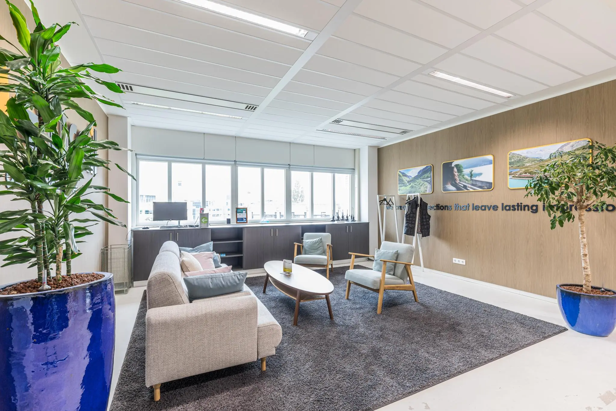 Wachtkamer met moderne zithoek, grote planten in blauwe potten en wanddecoratie in het Leidseveer-gebouw.