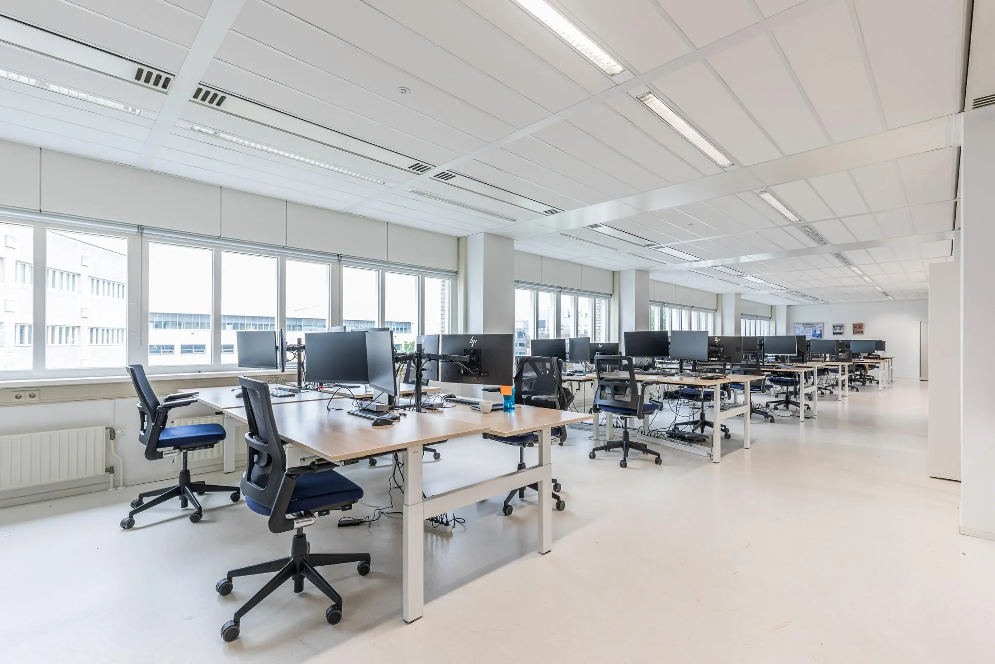 Moderne, open kantoortuin in het Leidseveer met bureaus, computerschermen en ergonomische bureaustoelen.