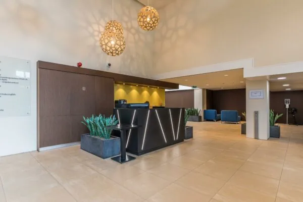 Moderne ontvangsthal van Leidseveer met een strakke balie, stijlvolle hanglampen en zitgedeelte met blauwe stoelen.