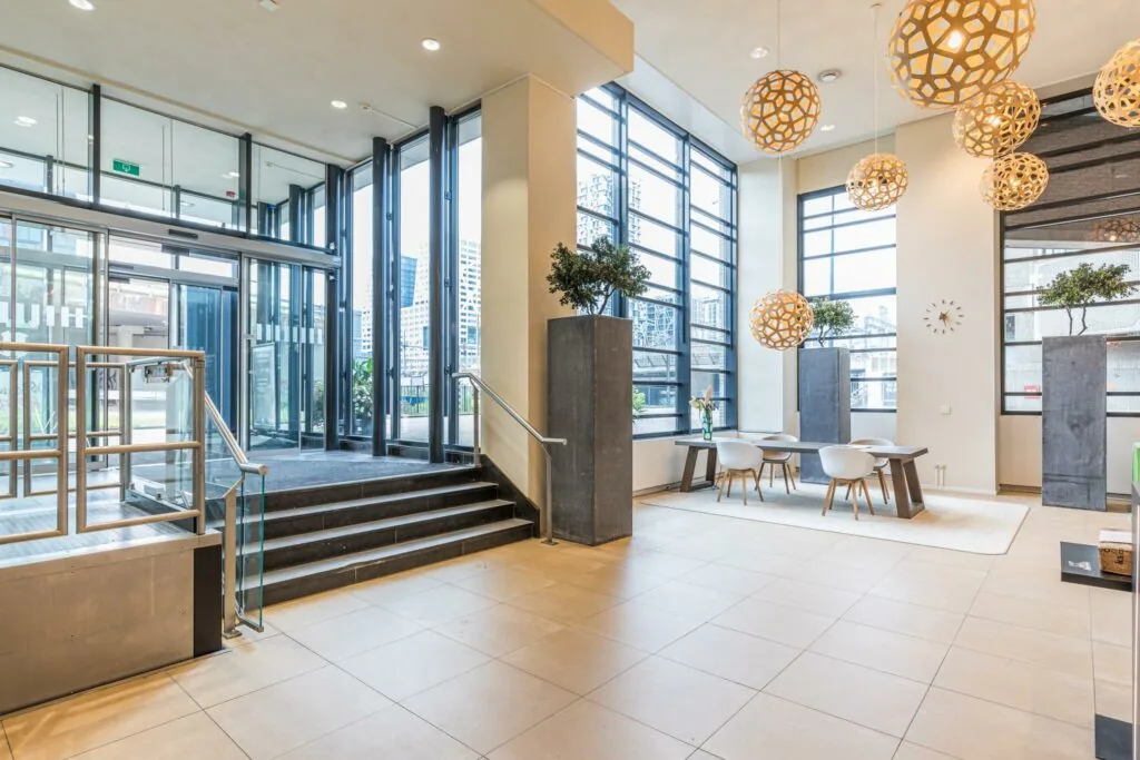 Moderne, lichte entree van het gebouw Leidseveer met grote ramen, designverlichting en een zitgedeelte.