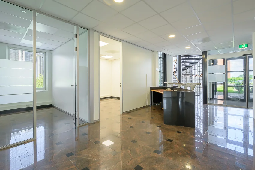 Moderne kantoorruimte aan de Rivium Westlaan met glazen wanden, receptiebalie en zicht op een buitentrap.