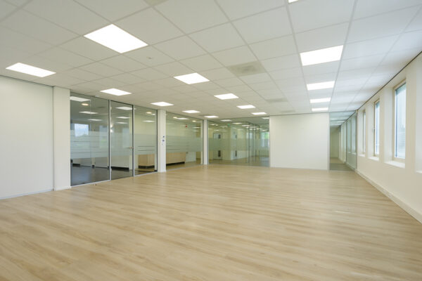 Licht en modern kantoorpand aan de Rivium Westlaan met houten vloer, systeemplafond en glazen scheidingswanden.