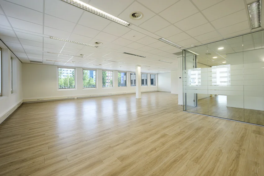 Lichte, lege kantoorruimte aan de Rivium Westlaan met houten vloer en glazen vergaderruimte.
