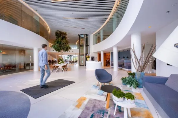Moderne en ruime ontvangsthal aan de Euclideslaan met zithoeken, planten en een centraal gelegen receptiebalie.