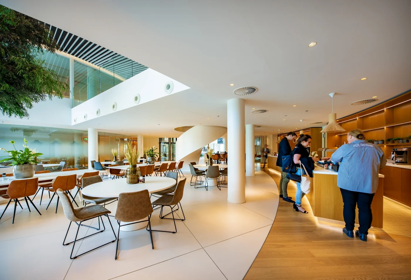 Moderne en lichte kantoorkantine aan de Euclideslaan met ronde tafels, designstoelen en een koffiebar.