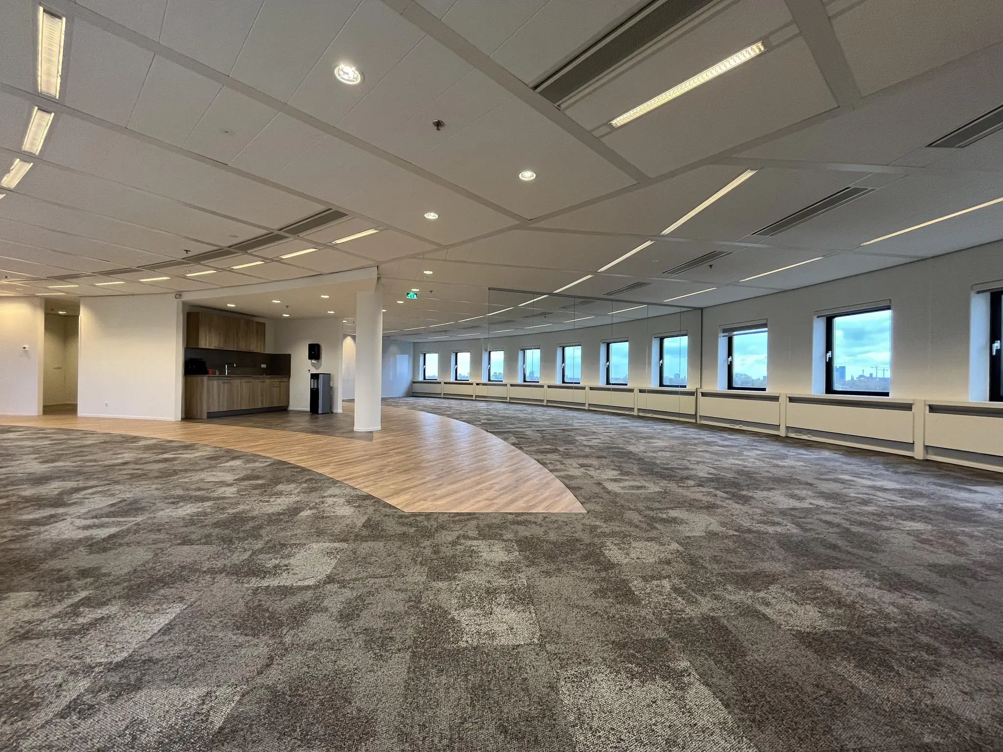 Modern, leeg kantoorpand aan de Euclideslaan met tapijtvloer, grote ramen en een kitchenette.