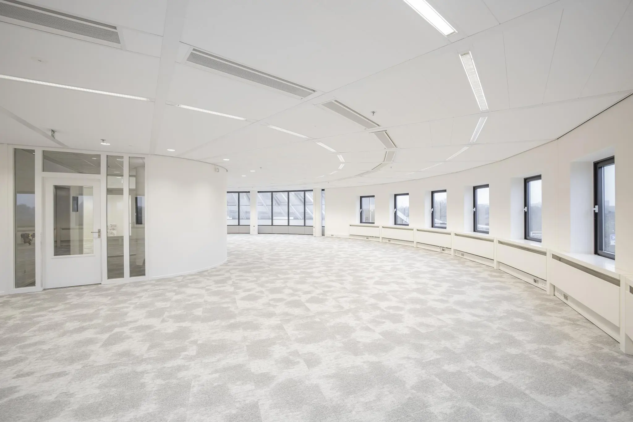 Licht en modern kantoorinterieur aan de Euclideslaan met gebogen raamwand en glazen deur.