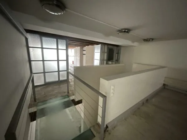 Gang met glazen loopbrug en wit gestucte muren in een pand aan het Entrepotdok.