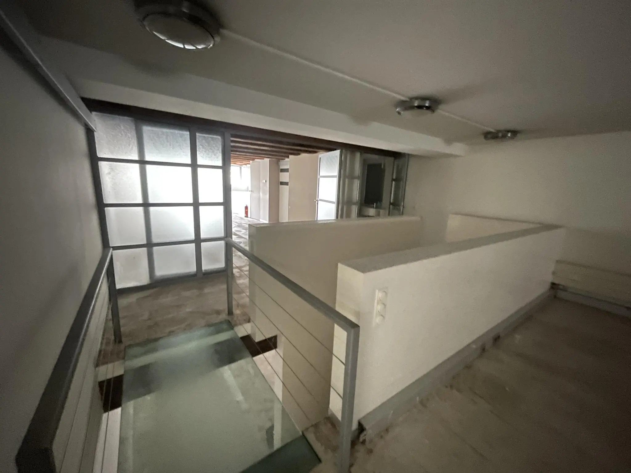 Gang met glazen loopbrug en wit gestucte muren in een pand aan het Entrepotdok.