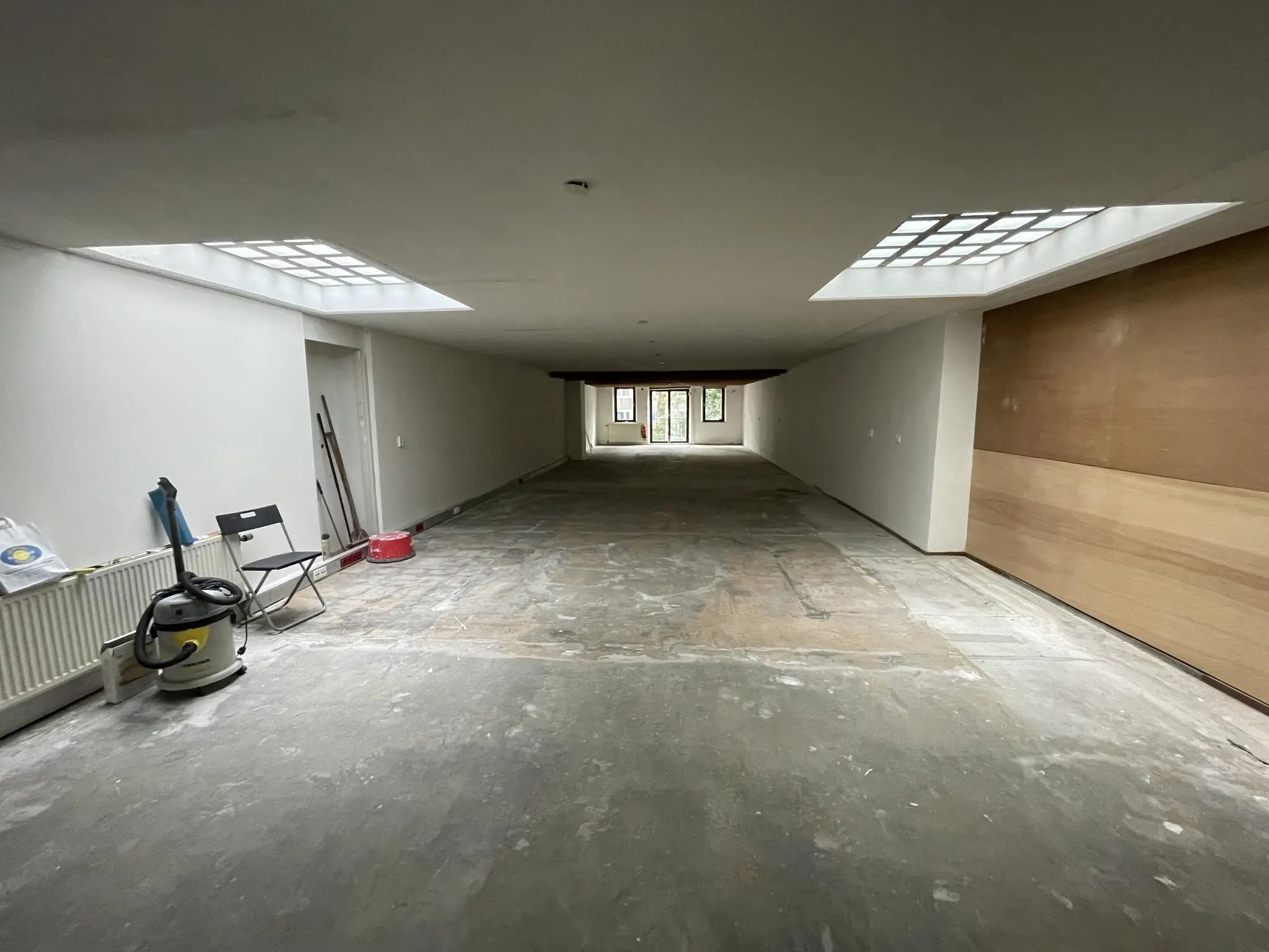 Lange, lege ruimte in renovatie met betonnen vloer en daglichttoetreding via twee lichtkoepels, gelegen aan het Entrepotdok.