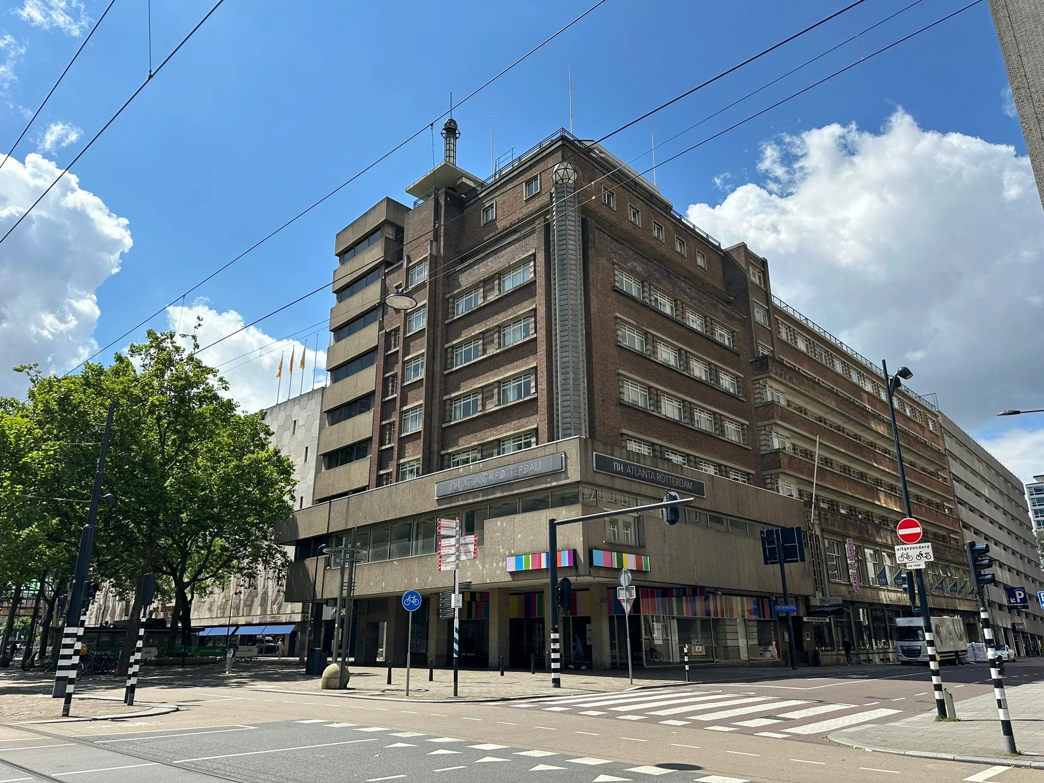 Het NH Atlanta Rotterdam hotel aan de Coolsingel op een zonnige dag met blauwe lucht en wolken.