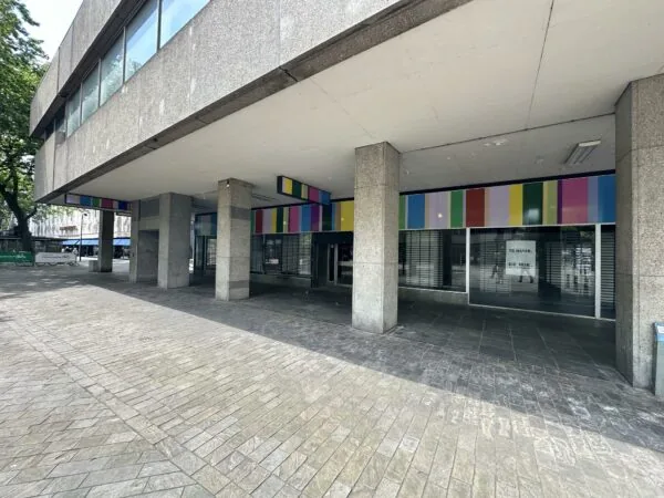 Leegstaand winkelpand aan de Coolsingel met gekleurde gevelpanelen en een 'Te huur' bord achter het raam.