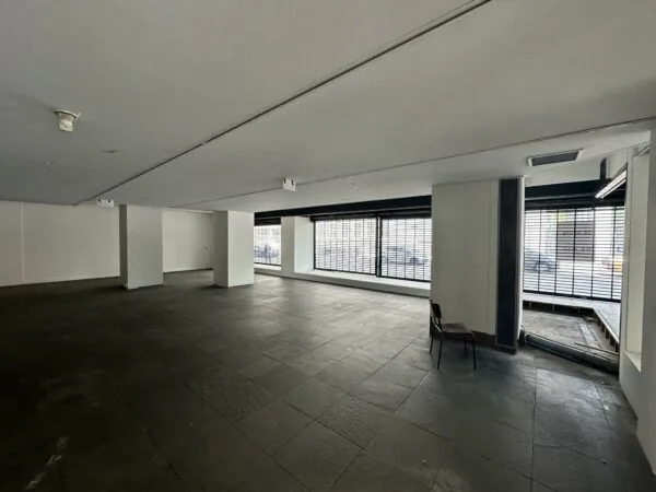 Leegstaand winkelpand aan de Coolsingel met grote ramen en zicht op de straat.