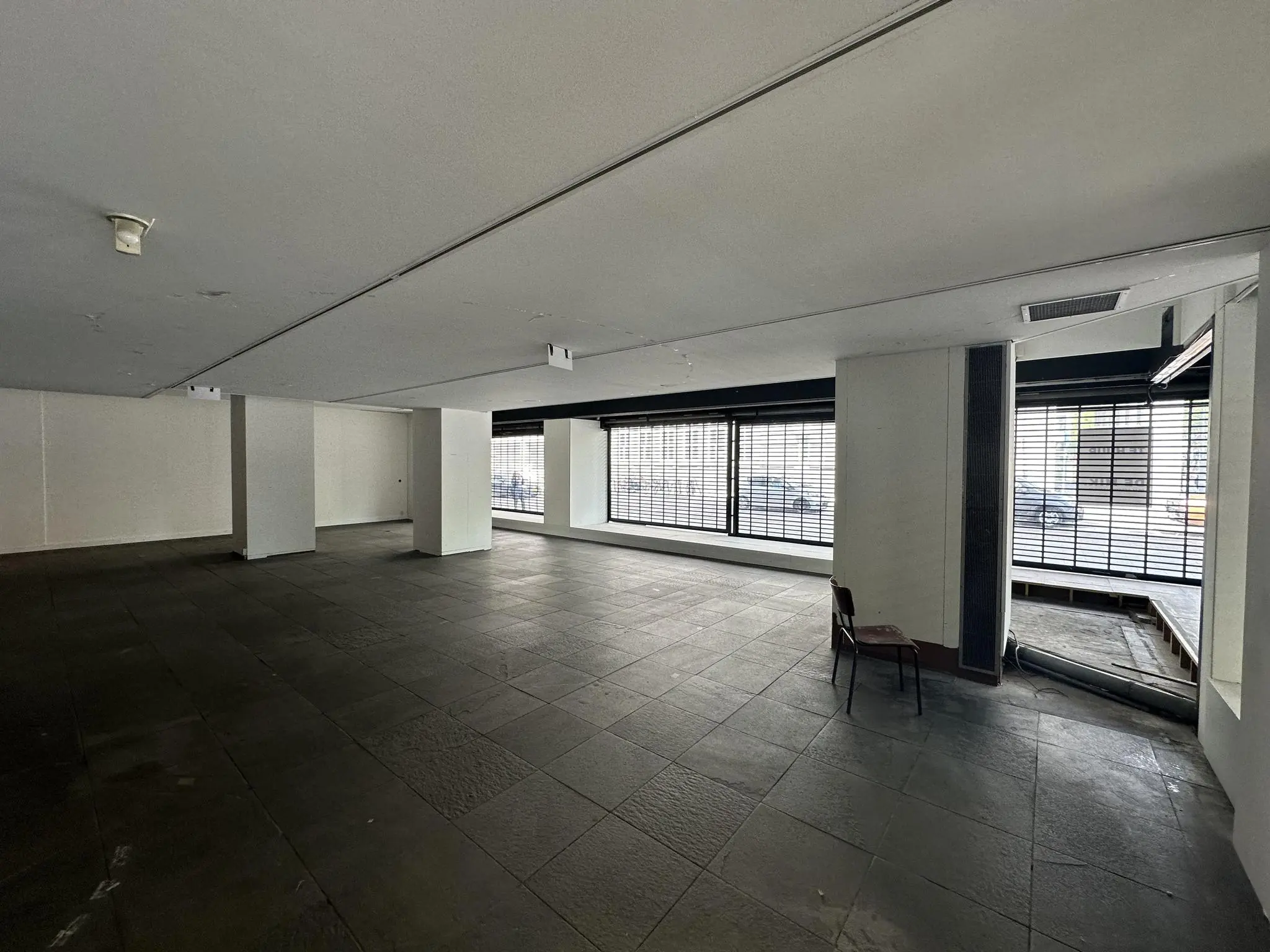 Leegstaand winkelpand aan de Coolsingel met grote ramen en zicht op de straat.