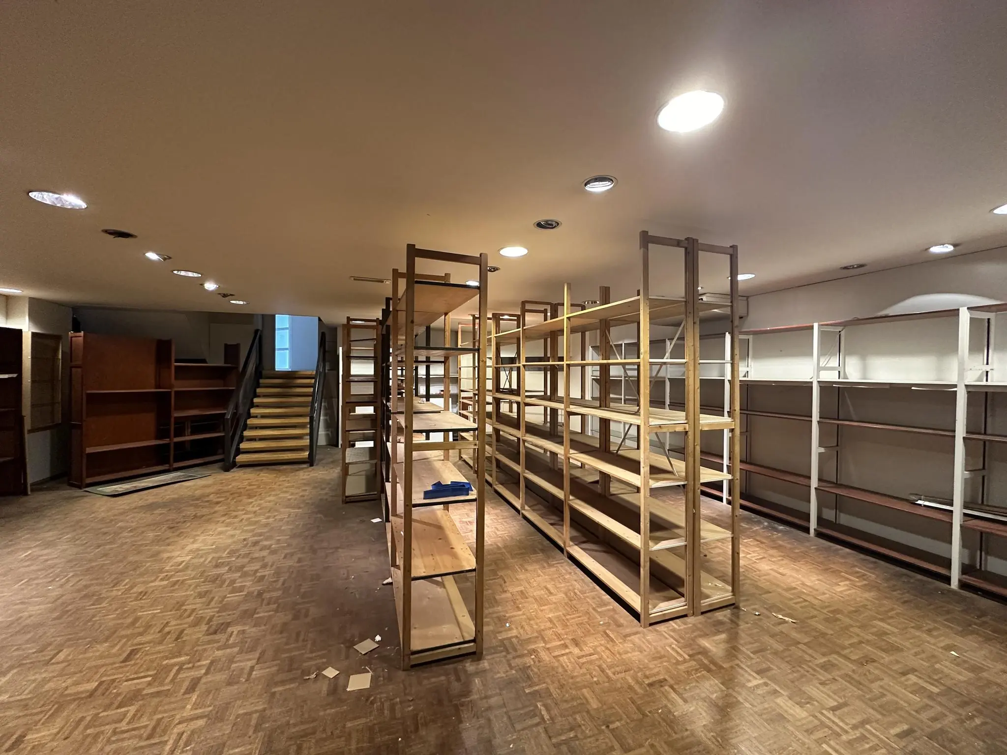 Lege winkelruimte met houten stellingen en trap, gefotografeerd aan de Coolsingel.