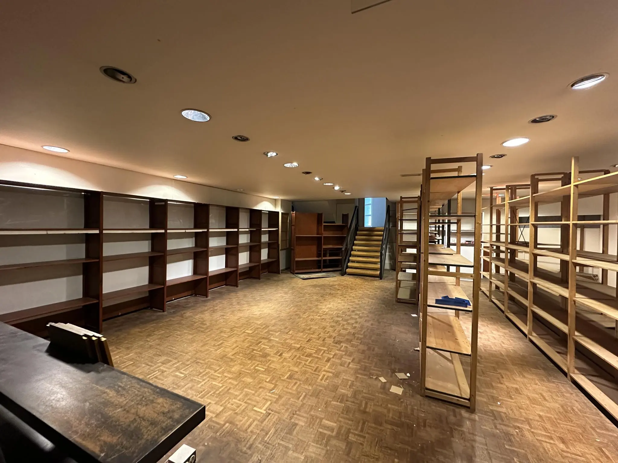 Leegstaande winkelruimte aan de Coolsingel met houten stellingen en een trap naar boven.