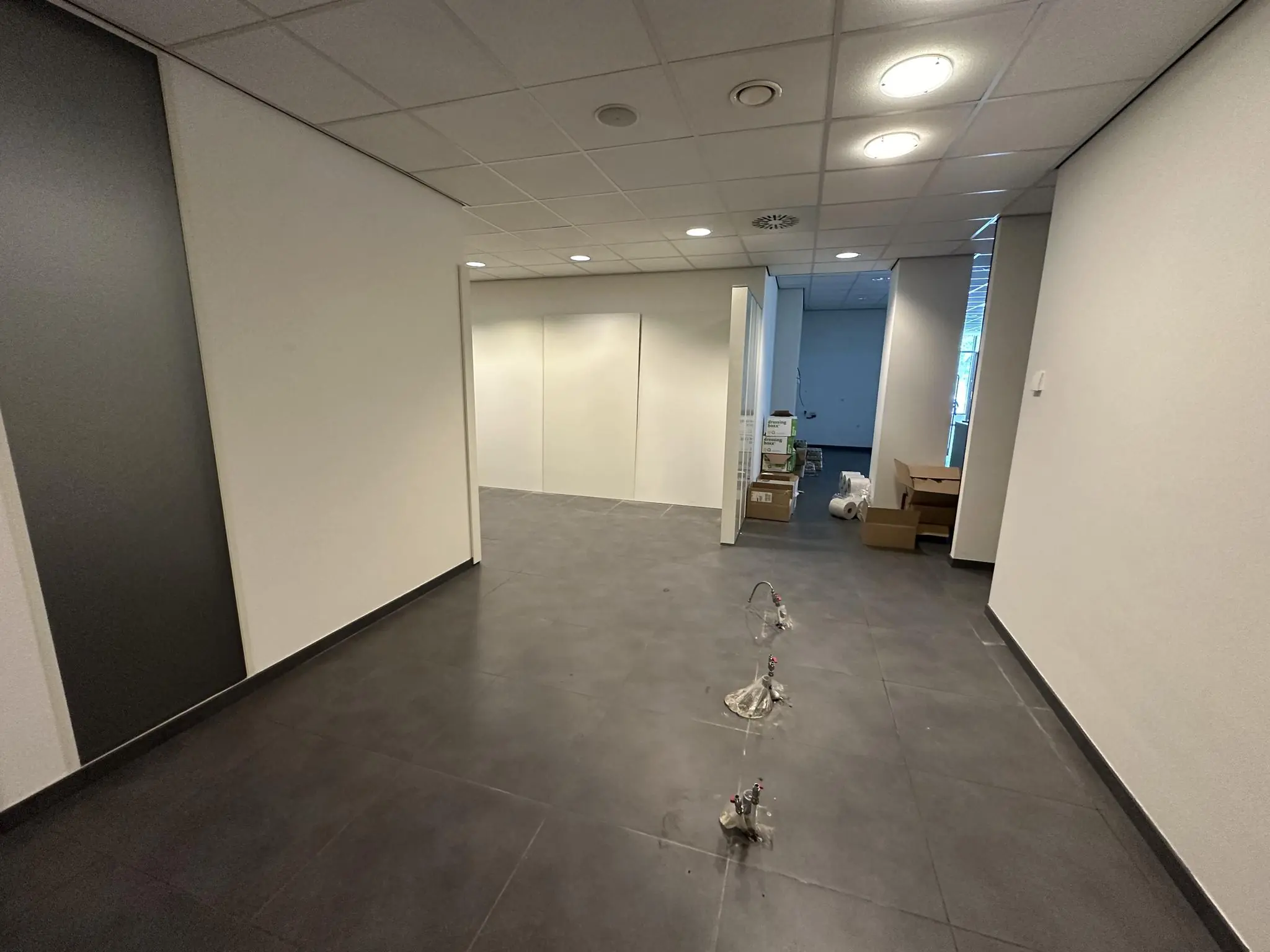 Lege kantoorruimte aan de Coolsingel in verbouwing met losse leidingen en stapels verhuisdozen.