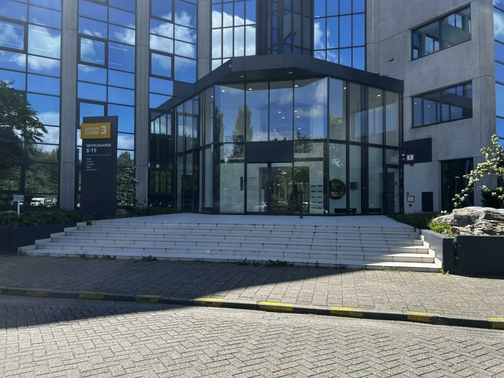 Ingang van kantoorgebouw Cloud 3 aan de Nevelgaarde 8-19 met glazen voorgevel en traptreden.