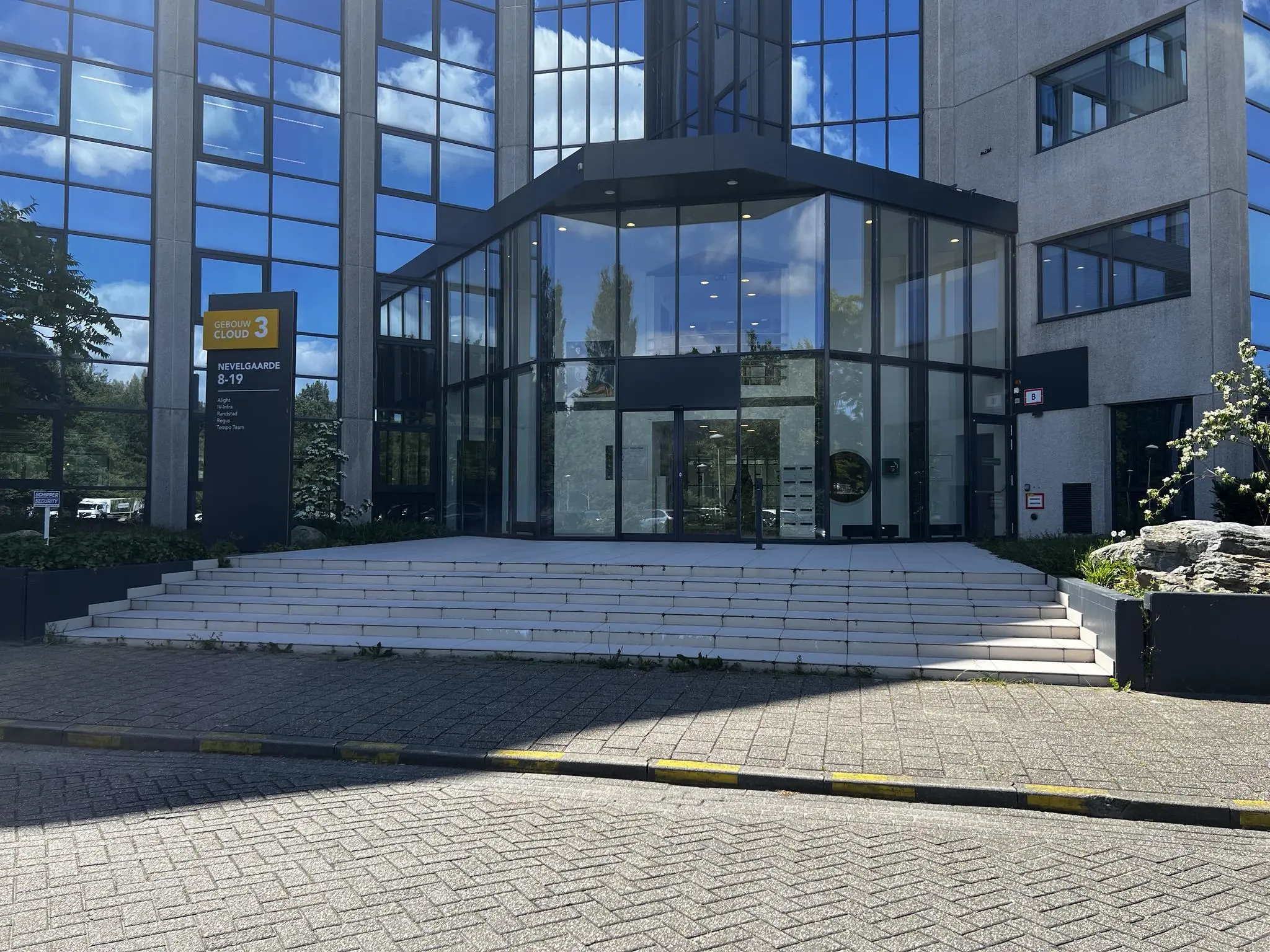 Ingang van kantoorgebouw Cloud 3 aan de Nevelgaarde 8-19 met glazen voorgevel en traptreden.