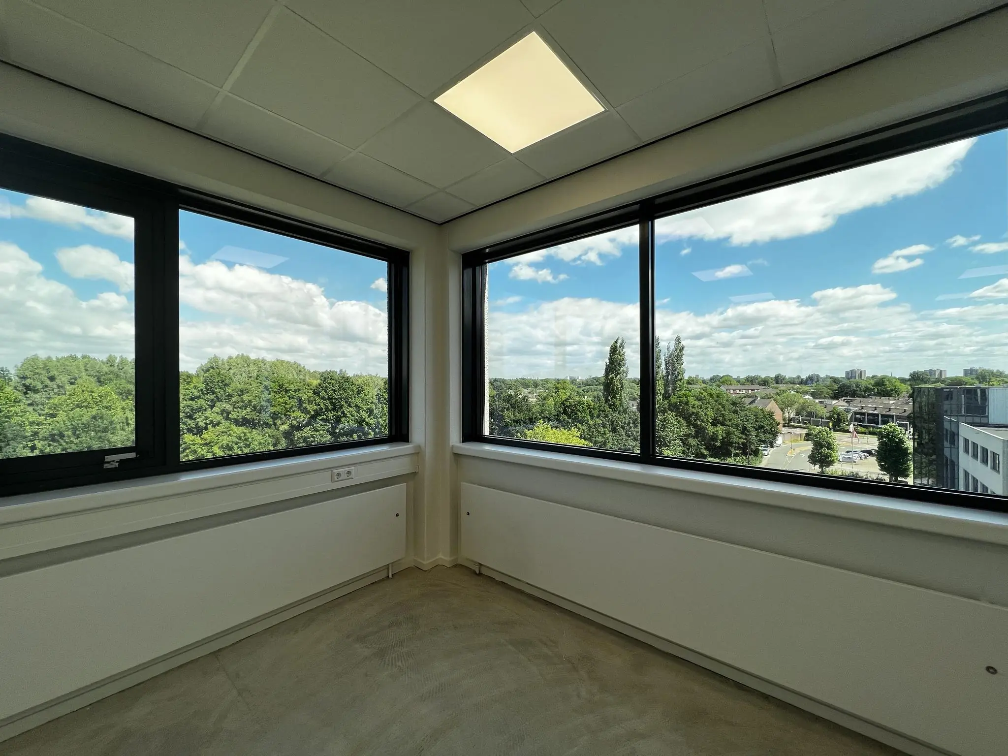 Leeg hoekkantoor in Nevelgaarde met grote ramen en uitzicht op een groene, stedelijke omgeving.