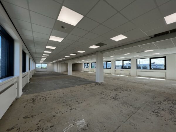 Leeg kantoorpand aan de Nevelgaarde met systeemplafond, grote raampartijen en onafgewerkte vloer.