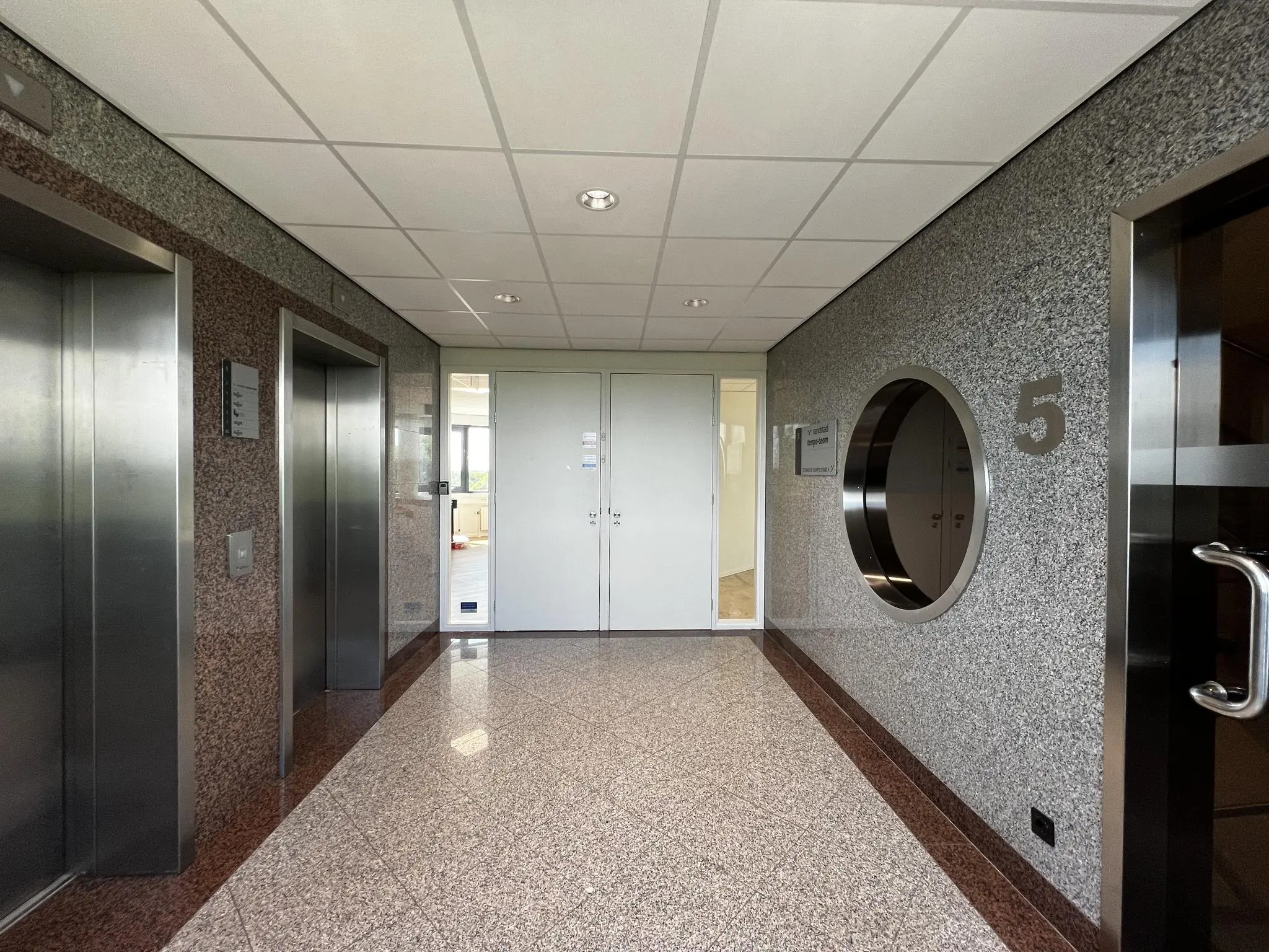 Entree van de vijfde verdieping in kantoorpand Nevelgaarde met twee liften, een glazen deur en een ronde inkijkopening in de muur.