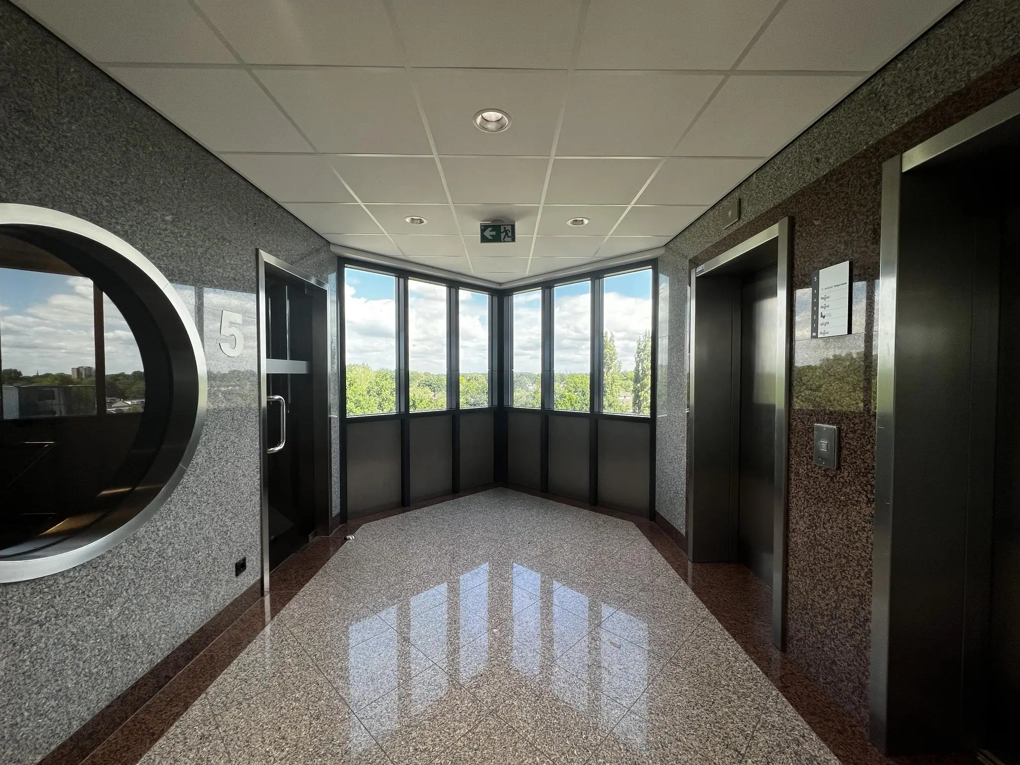 Licht en modern kantoorverdieping met liftdeuren en raamuitzicht op de vijfde etage van gebouw Nevelgaarde.
