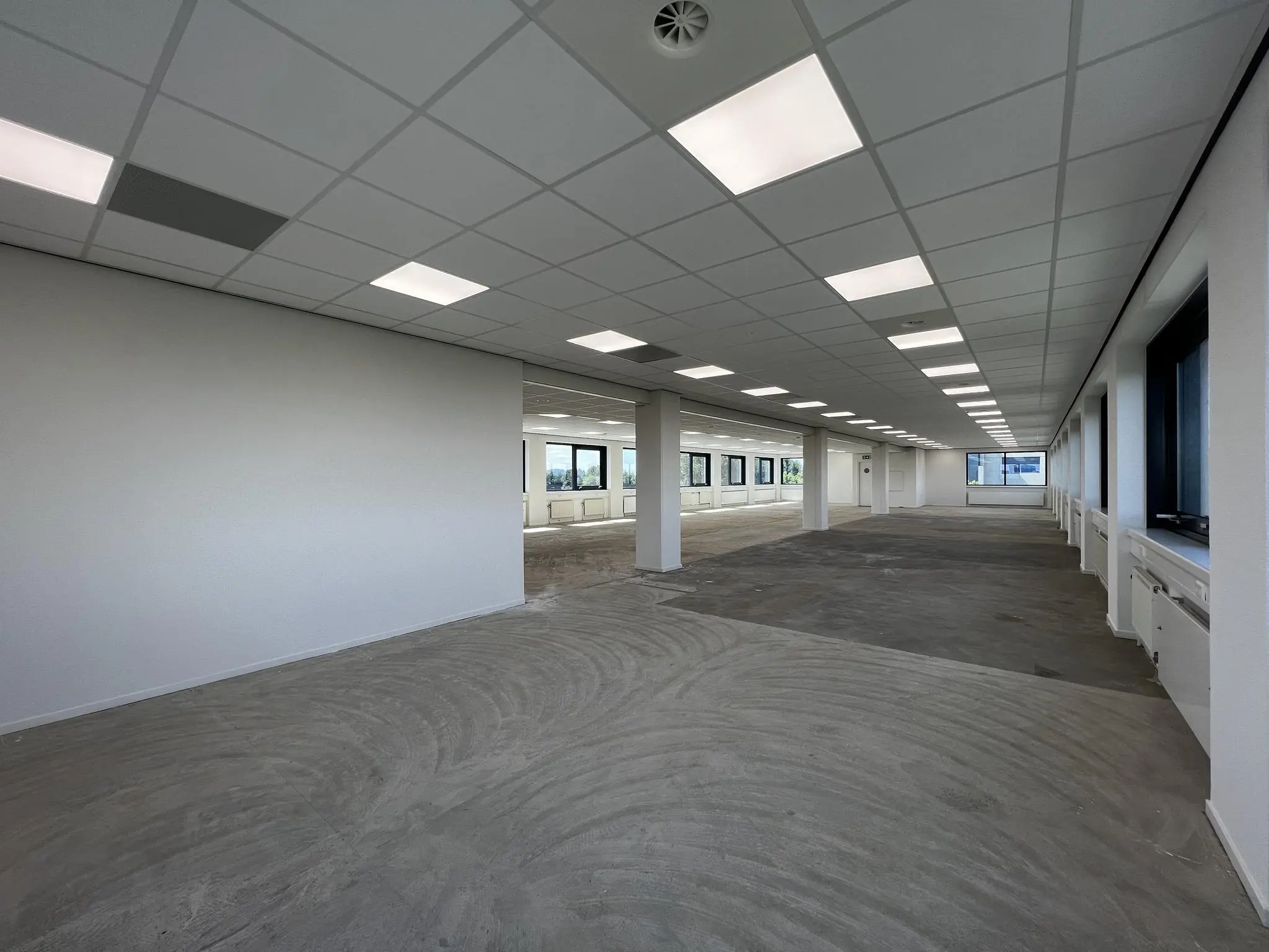 Leeg kantoorpand aan de Nevelgaarde met systeemplafond, raamkozijnen en onafgewerkte vloer.