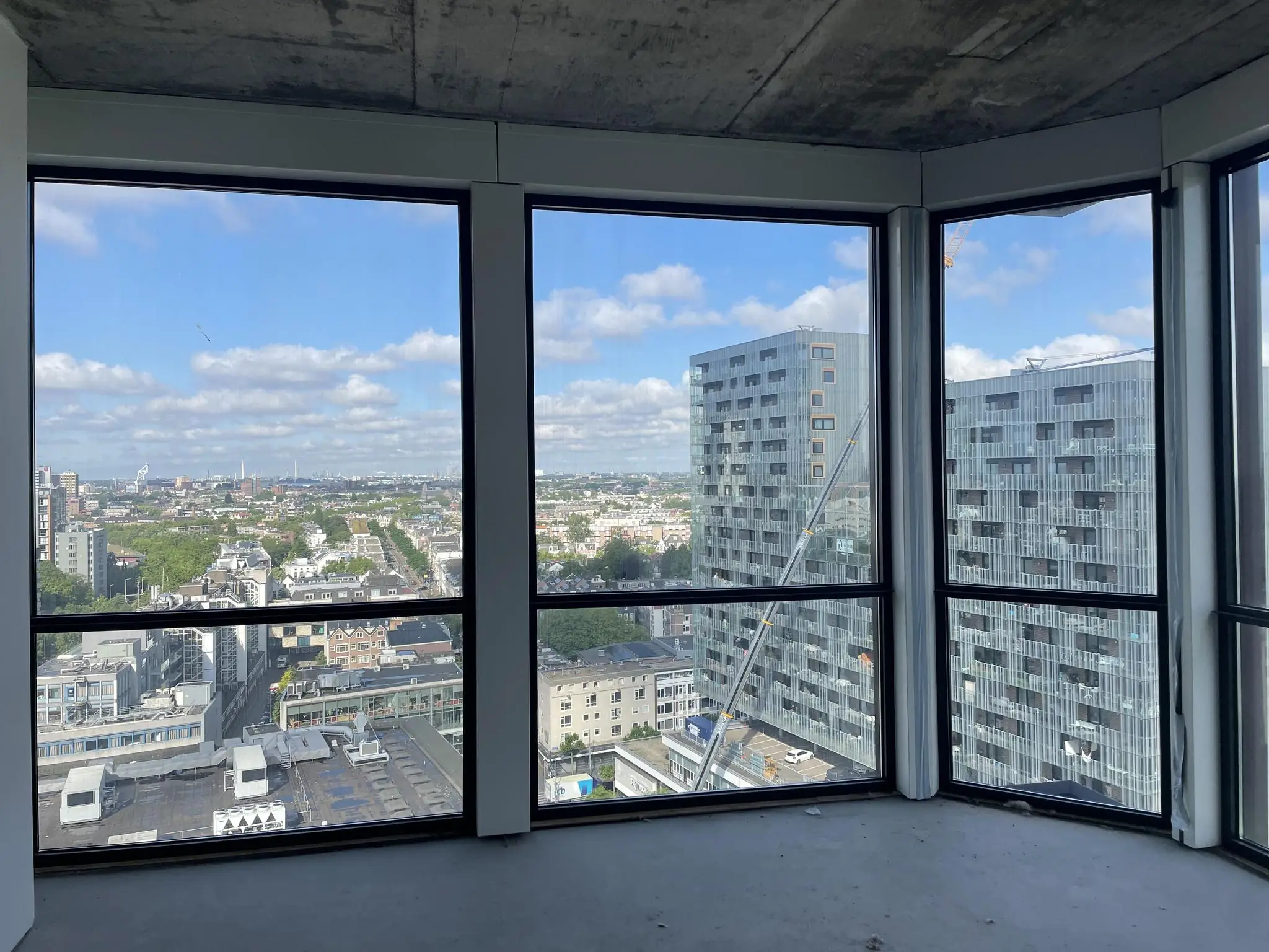 Uitzicht vanuit een leeg appartement op de Coolsingel in Rotterdam met moderne hoogbouw en een weids stadszicht.