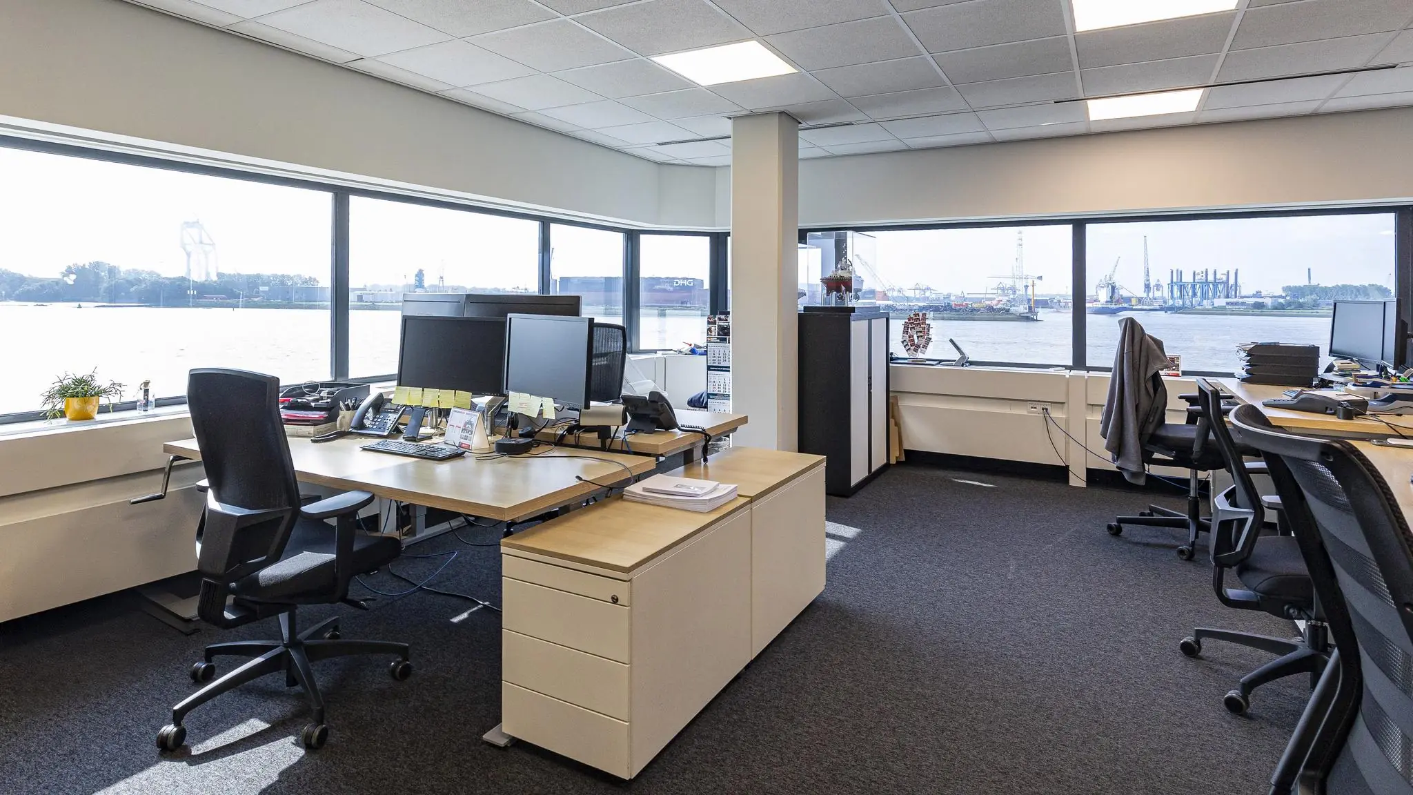 Modern kantoor met uitzicht op de haven aan de Havenstraat, met bureaus, computers en grote ramen.
