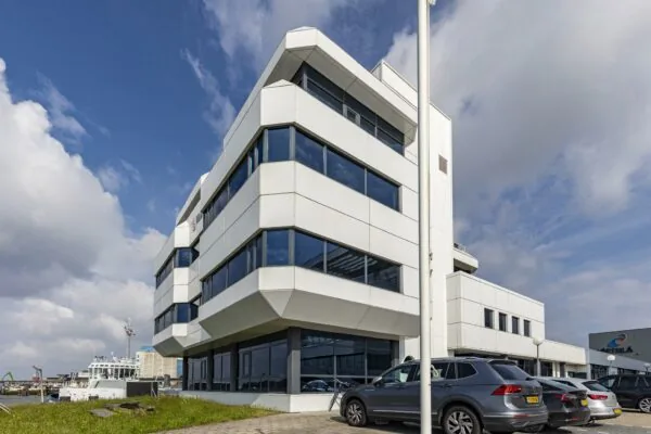 Modern wit kantoorgebouw aan de Havenstraat met geparkeerde auto's en uitzicht op het water.