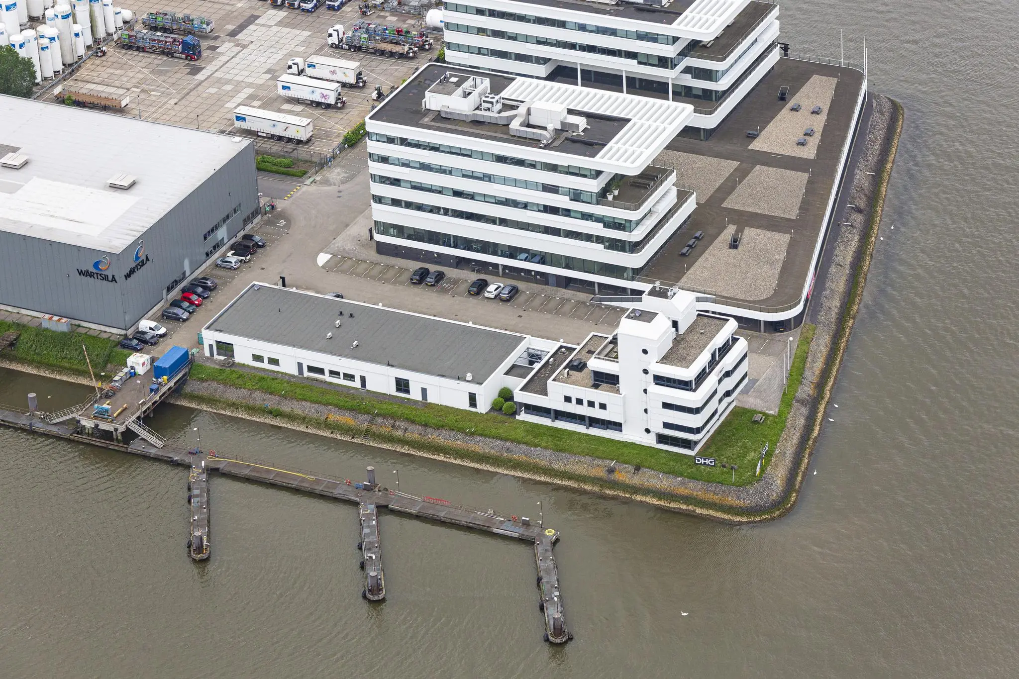 Luchtfoto van moderne kantoorgebouwen aan de Havenstraat met ligging direct aan het water en een aangrenzende bedrijfshal van Wärtsilä.