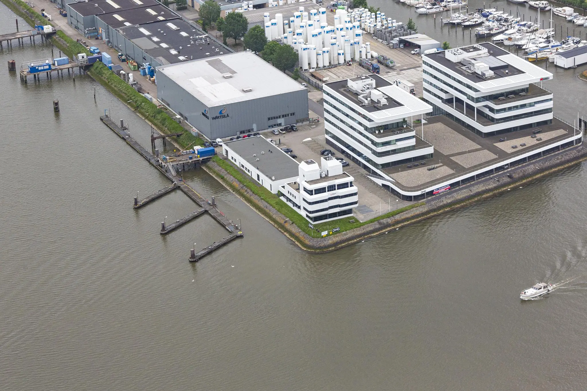Luchtfoto van moderne kantoorpanden en industriële gebouwen aan de Havenstraat langs het water met een passerende boot.
