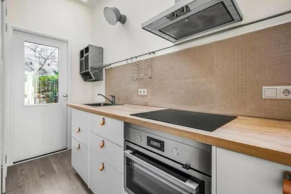 Moderne keuken in Westerstraat met houten werkblad, inductiekookplaat en ingebouwde oven.