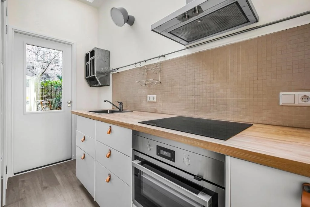 Moderne keuken in Westerstraat met houten werkblad, inductiekookplaat en ingebouwde oven.