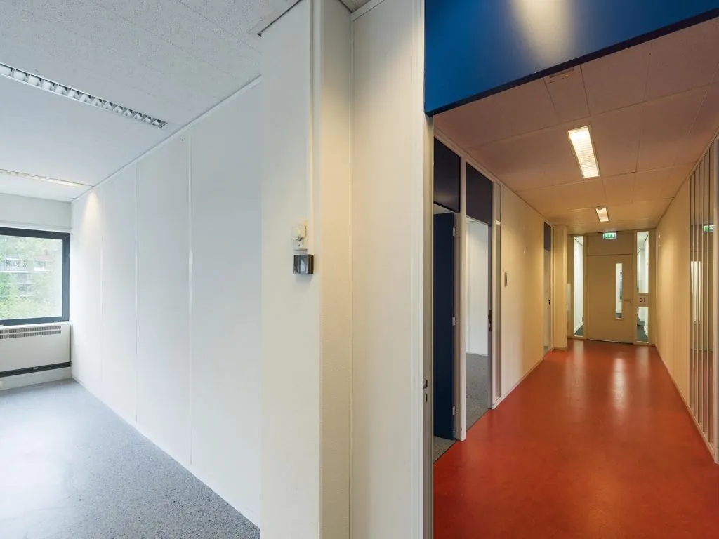 Geverfde gang met rode vloerbekleding en aangrenzende kantoorruimtes in gebouw Entrada 175, Amsterdam.