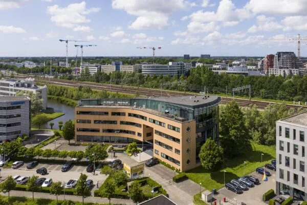 Kantoorgebouw aan de Wegalaan in Hoofddorp met parkeerplaatsen op de voorgrond en spoorlijnen op de achtergrond.