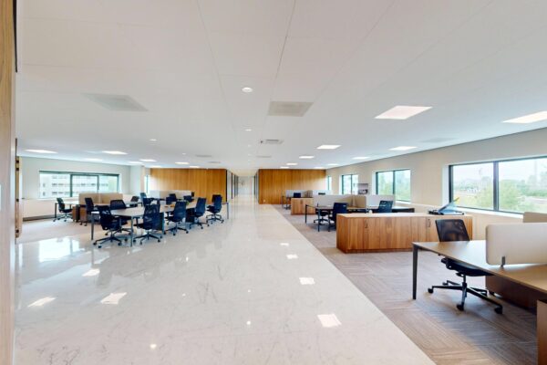 Moderne open kantooruimte aan de Wegalaan met ruime bureaus, bureaustoelen en grote ramen die veel daglicht binnenlaten.