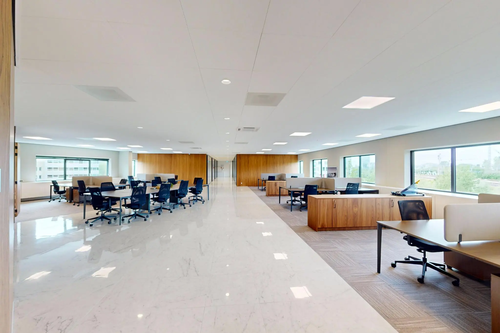 Moderne open kantooruimte aan de Wegalaan met ruime bureaus, bureaustoelen en grote ramen die veel daglicht binnenlaten.