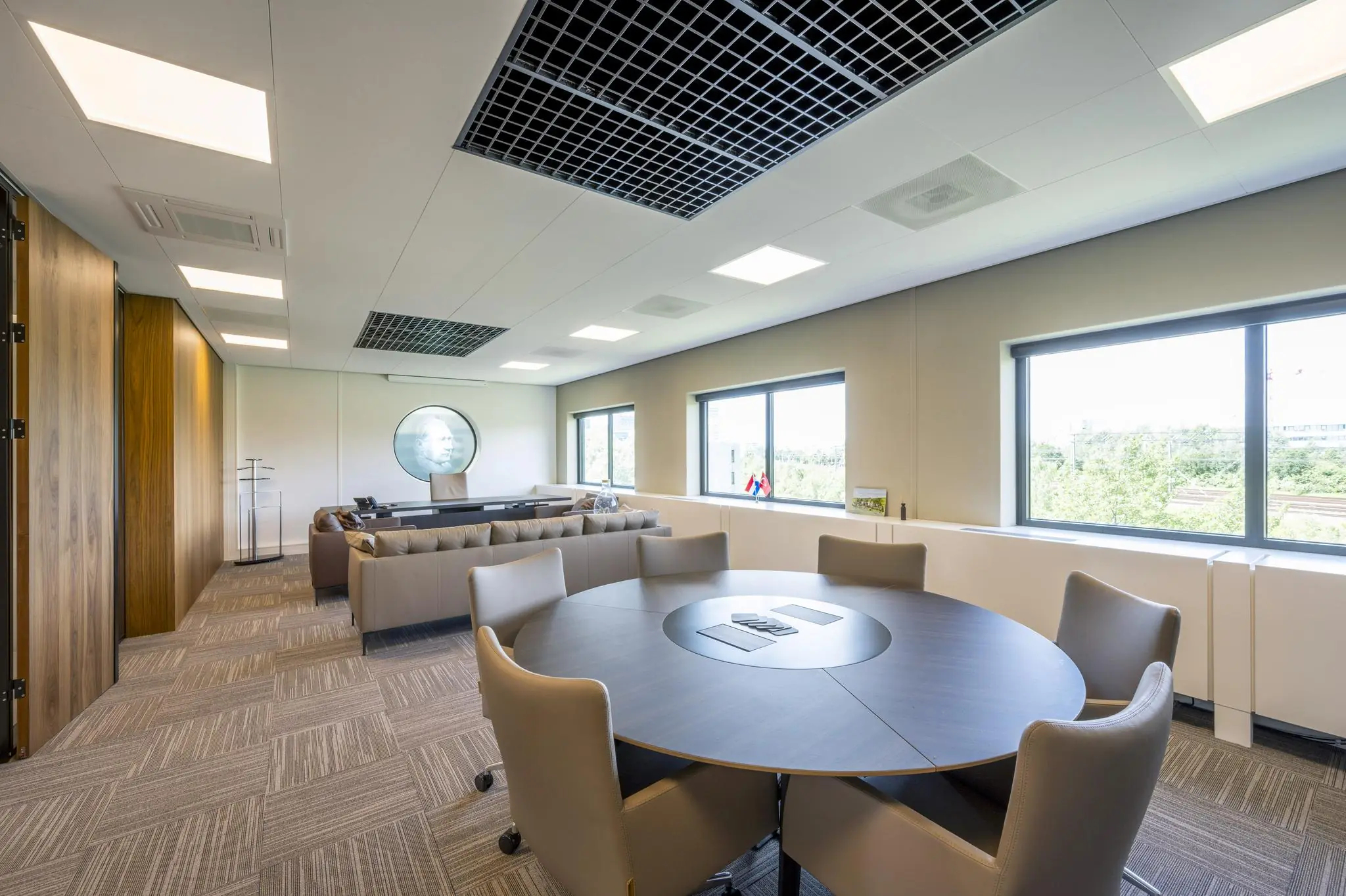 Modern kantoorinterieur aan de Wegalaan met vergadertafel, zithoek en uitzicht op groen landschap.