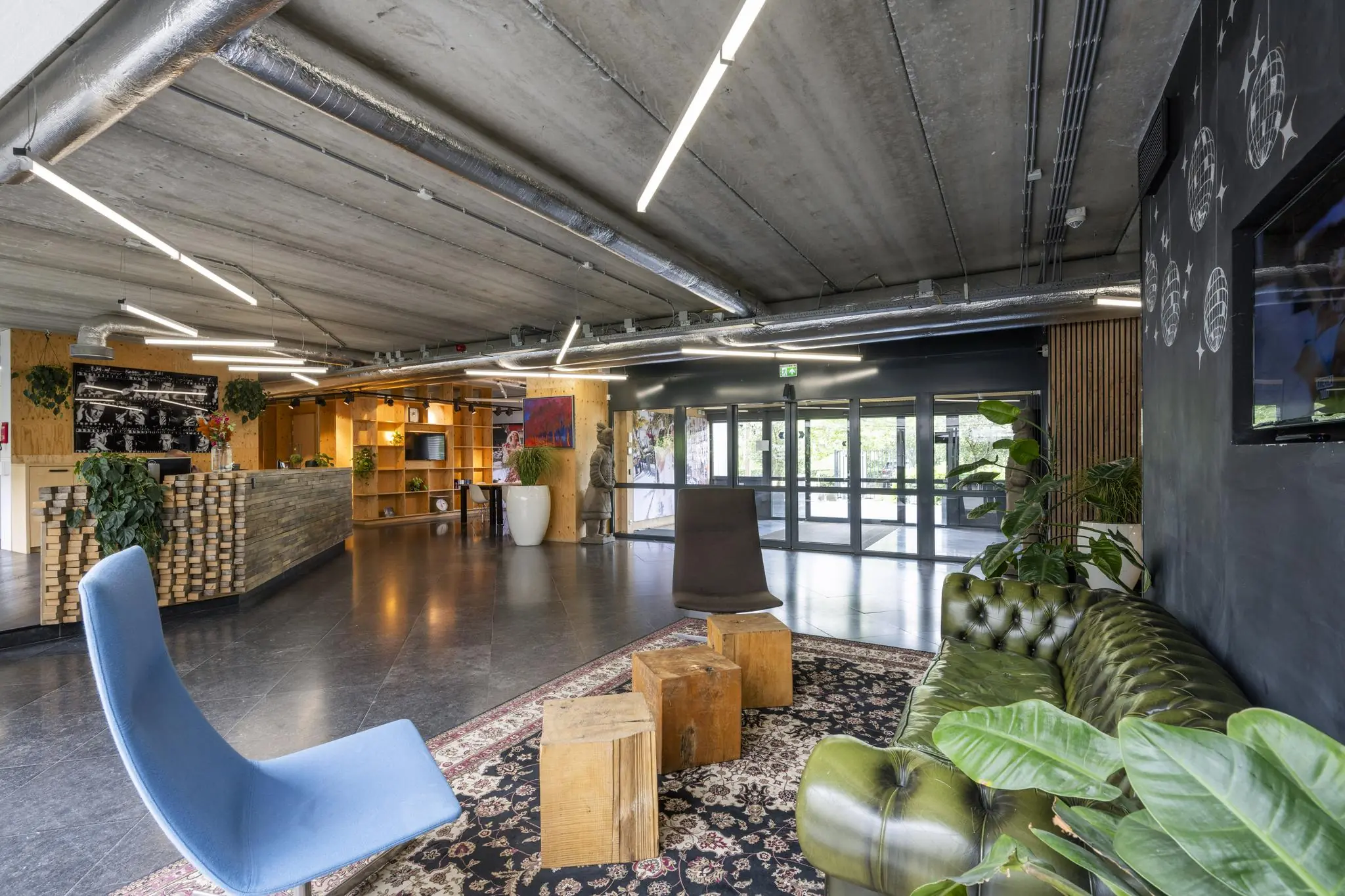 Moderne en sfeervolle lobby van Diemermeer met industriële inrichting, designmeubilair en veel groen.
