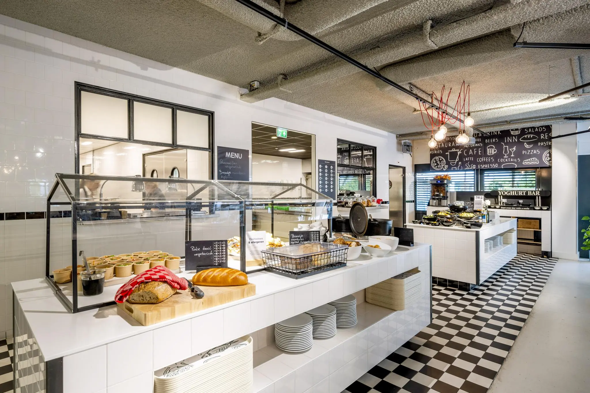Modern buffetrestaurant Diemermere met open keuken, vers brood, saladecups en een yoghurtbar op een zwart-wit geblokte tegelvloer.