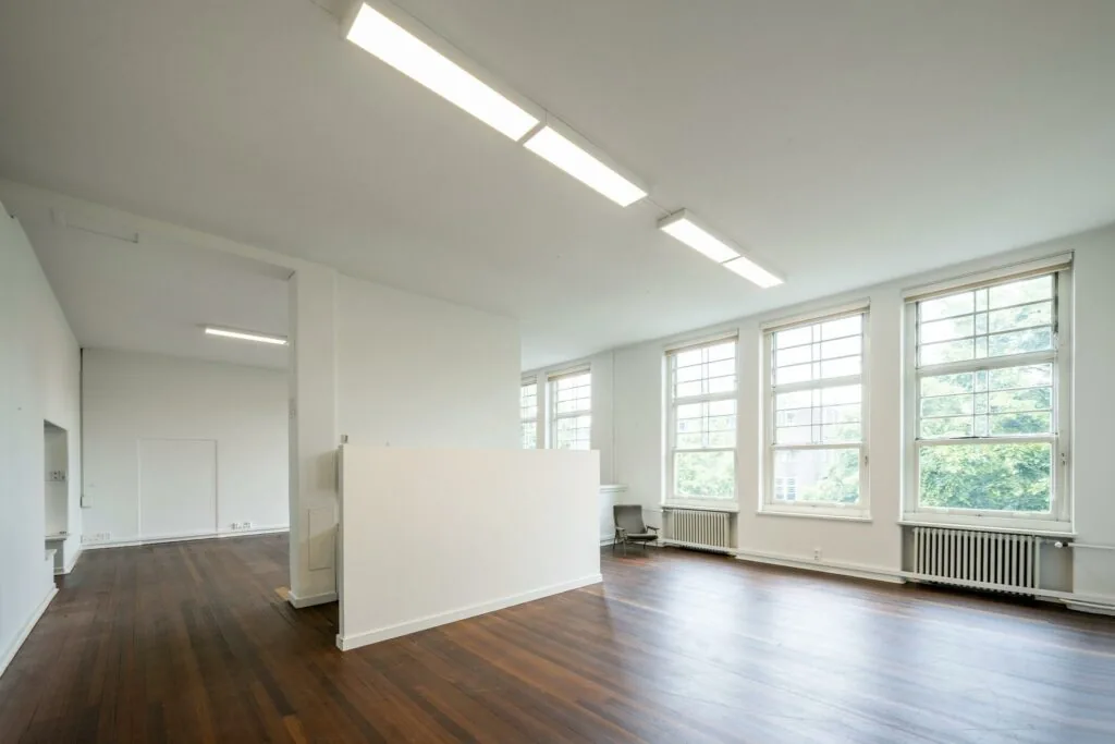 Lichte, lege ruimte met houten vloer en grote ramen aan het WG-plein.