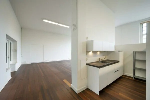 Moderne, lichte ruimte met een open keuken en donkerhouten vloer in een pand aan het WG-plein.