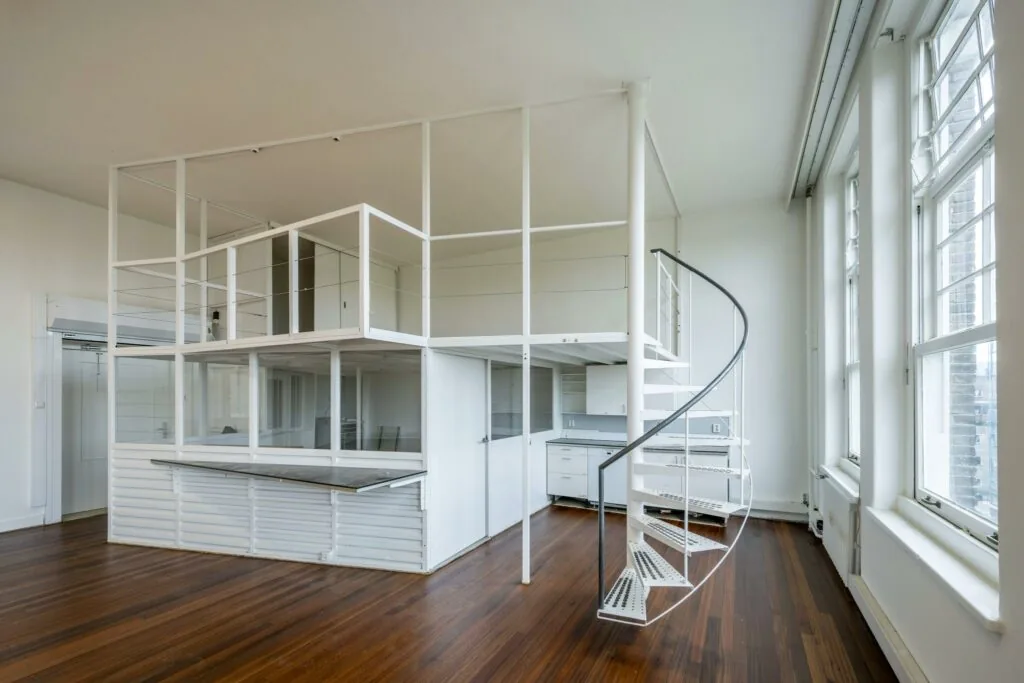 Moderne witte loftwoning aan het WG-plein met een open tussenverdieping en een spiraaltrap.