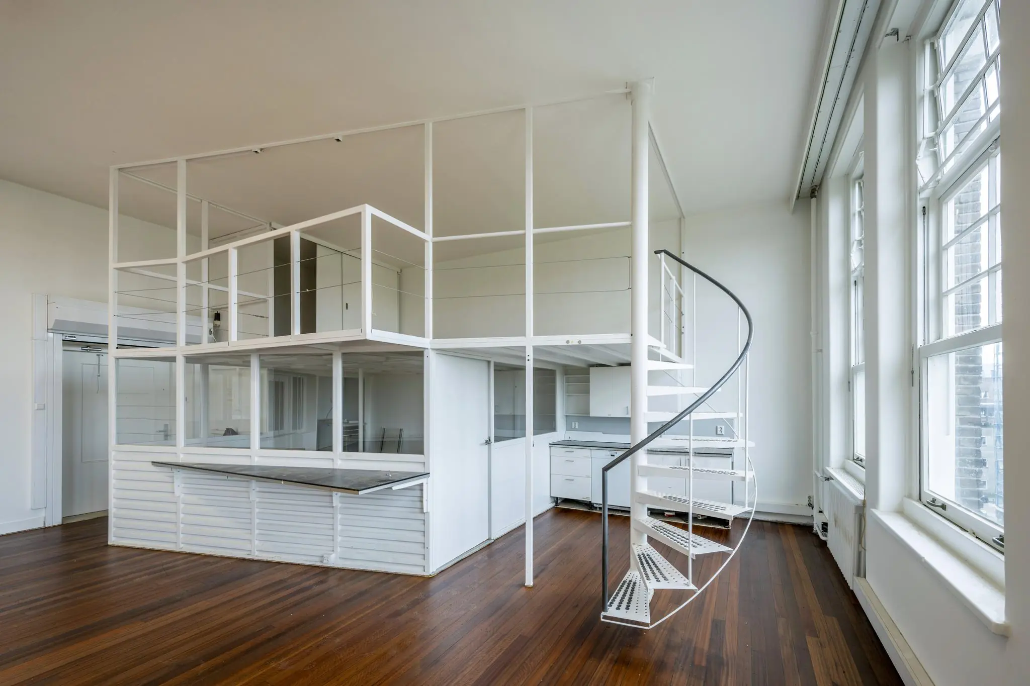 Moderne witte loftwoning aan het WG-plein met een open tussenverdieping en een spiraaltrap.